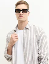 Camisa de lino a rayas verticales color beige y blanco, de corte clásico, con cuello abotonado y mangas largas.