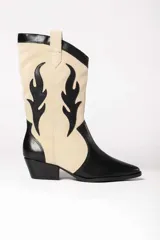 Bota estilo texana con diseño bicolor en negro y beige. Presenta una combinación de cuero liso negro en la puntera, talón y detalles superiores, con paneles de gamuza beige en la caña decorados con apliques de cuero negro en forma de llamas. Cuenta con taco cuadrado y punta fina.