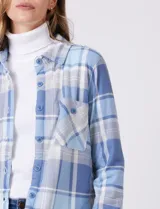 Sobrecamisa de tejido soft con estampado de cuadros en tonos azules y blancos. Presenta cuello con solapa, cierre frontal con botones, bolsillos aplicados en el pecho y mangas largas con puños abotonados. El interior cuenta con un acabado afelpado.