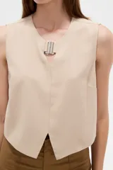 Musculosa cropped de viscosa color rosado, con cuello a la base, pequeña abertura frontal y detalle de hebilla metálica decorativa.