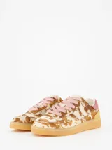 Championes de estilo urbano con estampado animal print tipo vaca en tonos marrones y beige. Presenta detalles en gamuza rosada en el talón, cordones rosados y suela de goma color caramelo.