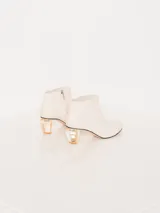 Bota de cuero color blanco con taco acrílico transparente y cierre lateral.