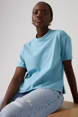 Remera celeste de manga corta, con cuello redondo y diseño holgado con aberturas laterales en el dobladillo.