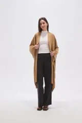 Poncho abierto de corte asimétrico y holgado, confeccionado en tejido de punto suave color beige, con mangas amplias y caída fluida.