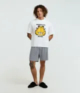 Pijama masculino de algodón, compuesto por una remera blanca con estampado de Garfield y la frase "Mondays Suck", y un short con rayas verticales blancas y negras. Incluye pantuflas negras de felpa.
