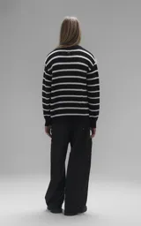 Sweater de cuello redondo con diseño de rayas horizontales en blanco y negro. Confeccionado en tejido de punto con textura suave, corte oversize y terminaciones en punto rib en cuello, puños y ruedo.