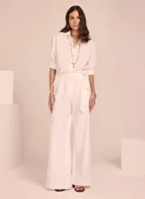 Camisa blanca de lino, de corte clásico, con cuello camisero y mangas largas con puños abotonados.