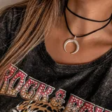 Gargantilla de cuero negro con dije de medialuna plateada.