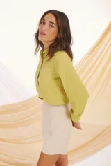 Camisa verde lima de manga larga con puños abullonados y botones dorados.