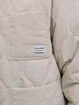 Campera acolchada liviana con diseño matelasse, cuello estilo baseball y cierre frontal con botones a presión. Cuenta con bolsillos frontales tipo parche y un bolsillo pequeño en el pecho con etiqueta de marca. Presenta puños elásticos y un corte recto funcional.