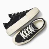 Championes Converse modelo Cruise Low Top, color negro con suela de plataforma de goma en tono crema. Presentan diseño de lona con costuras blancas visibles y cordones al tono.