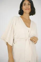 Bata maternal de algodón suave con diseño envolvente, escote en V y lazo ajustable en la cintura. Presenta mangas cortas holgadas y una silueta adaptable ideal para el embarazo y la lactancia.