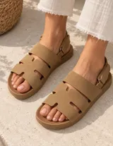 Sandalias de gamuza color beige con tiras anchas, aberturas laterales y tira en el talón con cierre ajustable.