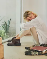 Botinetas de caña baja con suela track gruesa, combinando cuero negro en la puntera, gamuza marrón en el lateral y detalles de textura animal print tipo serpiente en tonos marrones. Presenta un cierre de solapa con velcro en el empeine.