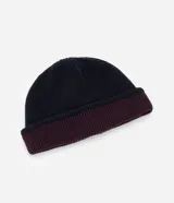 Gorro de punto con doblez, diseño reversible bicolor en tonos azul marino y bordó, confeccionado en lana acrílica.