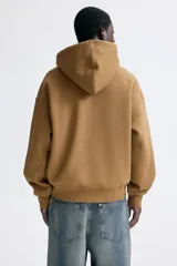 Campera con capucha H&M de corte oversized, color marrón, con cierre frontal y bolsillos tipo canguro.