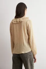 Blusa color beige de manga larga, con escote en V adornado con volados y cierre frontal con botones.