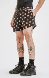 Short de baño de microfibra color negro con estampado de calaveras decoradas con flores y llamas en tonos pastel y vibrantes. Posee cordón ajustable en la cintura y un bolsillo trasero con ojalillo.