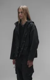 Campera técnica liviana de microfibra negra con acabado mate, capucha ajustable, cierre frontal oculto bajo solapa, bolsillos frontales con solapa y cordón ajustable en la cintura.