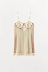 Vestido mini beige con aros de escote redondo y tirantes finos. Detalle de tejido combinado y costuras marcadas, con aplicación de encaje a tono y cierre en espalda con lazada.