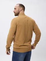 Sweater de tejido de punto color tostado, con cuello alto y cierre frontal parcial. Presenta mangas largas con puños acanalados y un diseño de corte clásico.