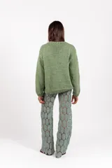Sweater de punto color verde, tejido y bordado a mano, con diseño gráfico artesanal en el frente y mangas largas.