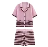 Conjunto de dos piezas tejido en punto, compuesto por una camisa de manga corta con cuello solapa, cierre frontal de botones y bolsillos delanteros, y un short con cintura elástica ajustable con cordón. Presenta un diseño a rayas horizontales en tonos rosa y marrón chocolate.