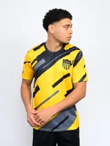 Remera de entrenamiento de Peñarol, con diseño estampado de líneas diagonales en amarillo, negro y gris. Presenta cuello redondo, mangas cortas y el escudo del club en el pecho.