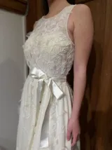 Vestido largo blanco de tul con escote redondo, detalles bordados y apliques en forma de flores.