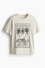 Remera de corte holgado con cuello redondo y estampado frontal gráfico que incluye palmeras, un tigre y la inscripción Coastal Oasis.
