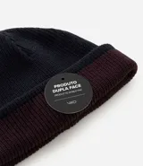 Gorro de punto con doblez, diseño reversible bicolor en tonos azul marino y bordó, confeccionado en lana acrílica.