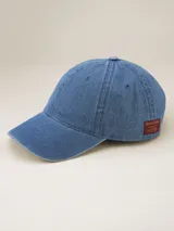 Gorra de gabardina color celeste con visera curva y etiqueta roja con letras bordadas en la parte trasera.