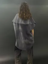 Poncho de lana merino afieltrada con cuello alto y mangas cortas. Diseño tipo mosaico con piezas geométricas en tonos verde azulado y gris.