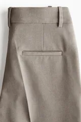 Pantalón tobillero de tejido elástico, color gris topo, con cintura estándar y elástico oculto. Presenta bolsillos al bies y bolsillos traseros decorativos.