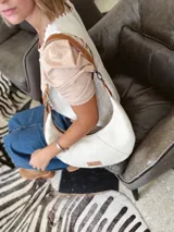 Cartera tipo hobo de cuero color crudo con correa de cuero marrón.