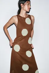 Vestido largo de punto marrón con cuello redondo y sin mangas, con estampado de lunares grandes en color crema.