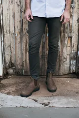 Bota marrón de cuero con elásticos laterales, tiradores delantero y trasero, y suela de goma negra.