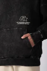 Buzo canguro oversize de algodón frizado con efecto gastado, capucha y bolsillo frontal tipo canguro. Presenta estampa gráfica sutil en el pecho.