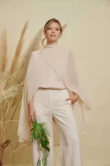 Capa de gasa color beige con cuello alto y diseño cruzado en el frente, de corte fluido y elegante.