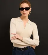 Blusa de punto ajustada color negro, con cuello polo y escote pronunciado en V. Presenta un tejido acanalado vertical en el torso y mangas largas.