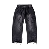 Pantalón baggy de corte holgado color negro con efecto acid wash, cintura elástica con cordón de ajuste y detalles de costuras y apliques de texto en el lateral de la pierna. Presenta dobladillos deshilachados.