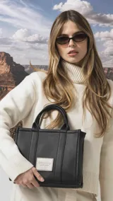 Cartera estructurada de tamaño mediano, confeccionada en símil cuero color negro. Presenta doble asa de mano, correa larga ajustable y desmontable, y un bolsillo trasero con cierre. El compartimento principal cuenta con cierre, división interna y bolsillos organizadores.