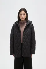 Campera acolchada de color negro con diseño capitoneado de ondas, manga larga, capucha integrada y cierre frontal con botones a presión.