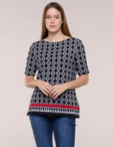 Remera de algodón con estampado geométrico en blanco y negro, de manga corta, con detalle de guarda roja y flecos en el ruedo.