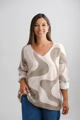 Sweater de punto amplio con escote en V y mangas largas, presenta un diseño estampado con ondas abstractas en tonos beige y verde oliva.