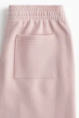 Pantalón de jogging de corte ancho y tiro alto, confeccionado en tejido de felpa con interior cepillado suave. Presenta cintura elástica fruncida con cordón de ajuste oculto, bolsillos laterales discretos y un bolsillo trasero abierto.