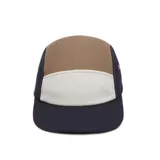 Gorra de cinco paneles Lacoste con diseño tricolor en tonos azul marino, beige y blanco. Presenta el logo del cocodrilo bordado en el lateral y ojales metálicos para ventilación.