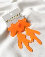 Aros colgantes de acrílico color naranja con formas abstractas.