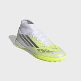 Championes de fútbol Adidas F50 Sparkfusion Club de caña media, diseñados para pasto sintético. Presentan un exterior en tonos blanco y amarillo neón con detalles plateados, tecnología Fiberskin para un mejor control del balón y suela Sprintplate Fusion para una tracción óptima.