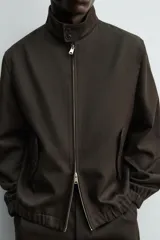Cazadora de corte regular confeccionada en tejido de lana y algodón de origen italiano. Presenta cuello alto ajustable con botones, cierre frontal con cremallera de doble dirección, bolsillos laterales con solapa y puños y ruedo con acabado elástico.